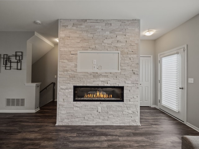 unfurnished living room featuring baseboards, dark wood-style flooring, and a stone fireplace