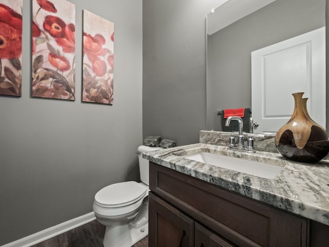 bathroom with wood finished floors, vanity, toilet, and baseboards