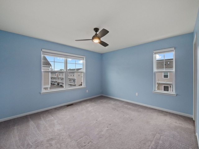 carpeted empty room featuring a ceiling fan and baseboards