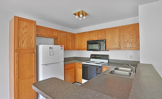 kitchen with black microwave, electric range, a sink, freestanding refrigerator, and dark countertops
