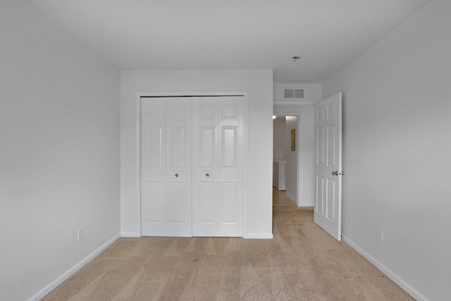unfurnished bedroom featuring light carpet, baseboards, and a closet