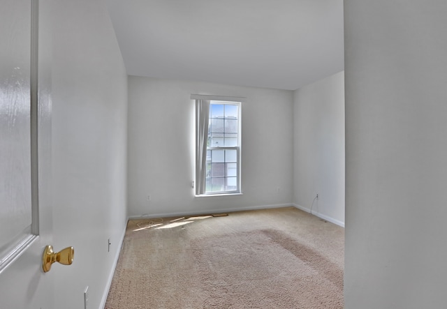 carpeted empty room featuring baseboards
