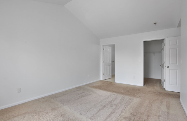 unfurnished bedroom with carpet flooring, vaulted ceiling, a spacious closet, baseboards, and a closet