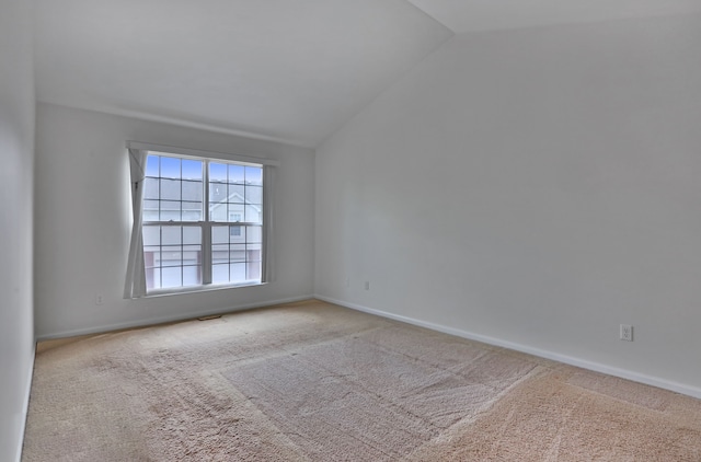 carpeted empty room featuring lofted ceiling and baseboards