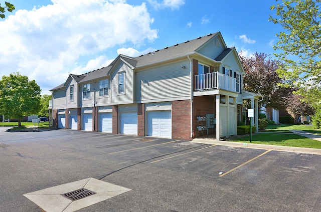 view of home's exterior with brick siding, a balcony, and uncovered parking