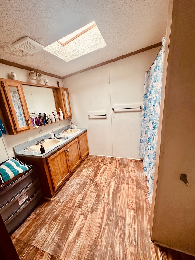 1832 E Carson City Rd, Sheridan, MI 48884 - full bathroom featuring a skylight, a textured ceiling, crown molding, wood finished floors, and double vanity