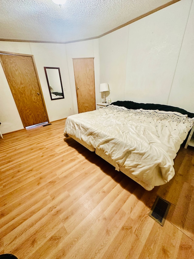 1832 E Carson City Rd, Sheridan, MI 48884 - bedroom with light wood-type flooring, a textured ceiling, and ornamental molding