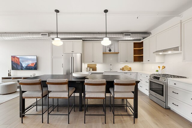 2051 Villa Rd Unit 204, Birmingham, MI 48009 - kitchen featuring appliances with stainless steel finishes, under cabinet range hood, open shelves, and a kitchen bar