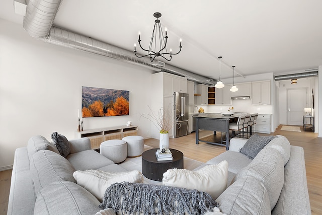 2051 Villa Rd Unit 204, Birmingham, MI 48009 - living room featuring light wood-style floors, a chandelier, and baseboards