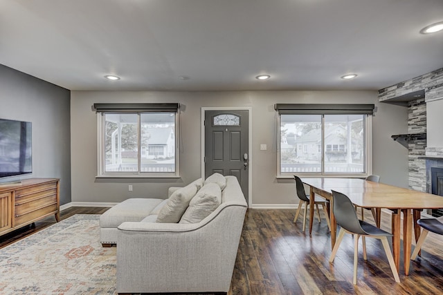 living area with baseboards, dark wood-style floors, a large fireplace, and recessed lighting