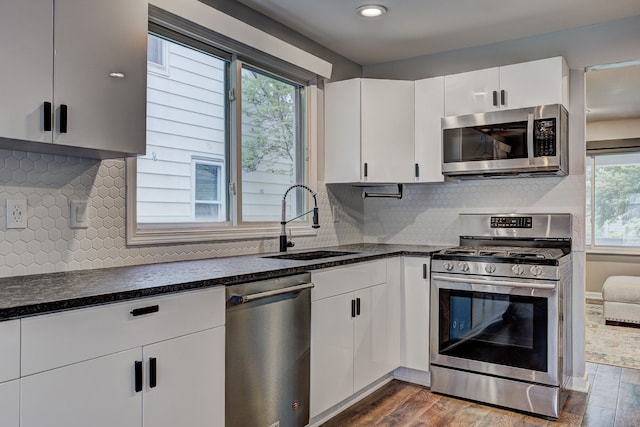 kitchen featuring appliances with stainless steel finishes, a sink, dark wood-style floors, white cabinets, and recessed lighting