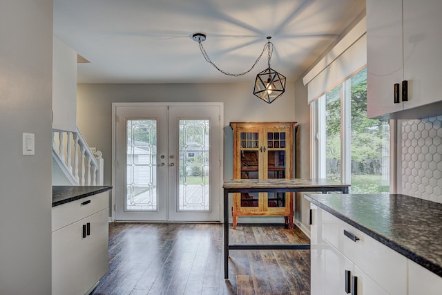 kitchen featuring dark wood finished floors, white cabinetry, french doors, decorative light fixtures, and dark stone counters