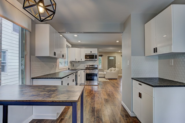 kitchen featuring stainless steel appliances, dark countertops, dark wood-style floors, white cabinets, and recessed lighting