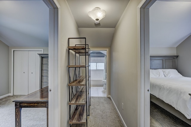 hallway featuring carpet flooring, baseboards, and lofted ceiling