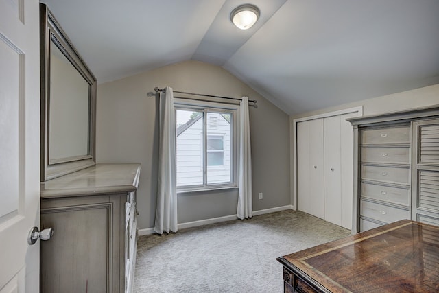 unfurnished office with light colored carpet, vaulted ceiling, and baseboards