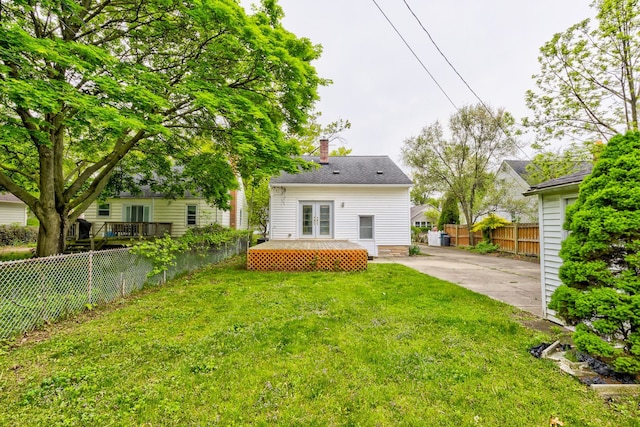 back of property with french doors, a chimney, and driveway