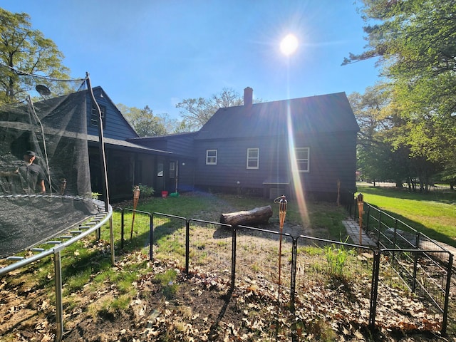 back of property with a chimney and a trampoline