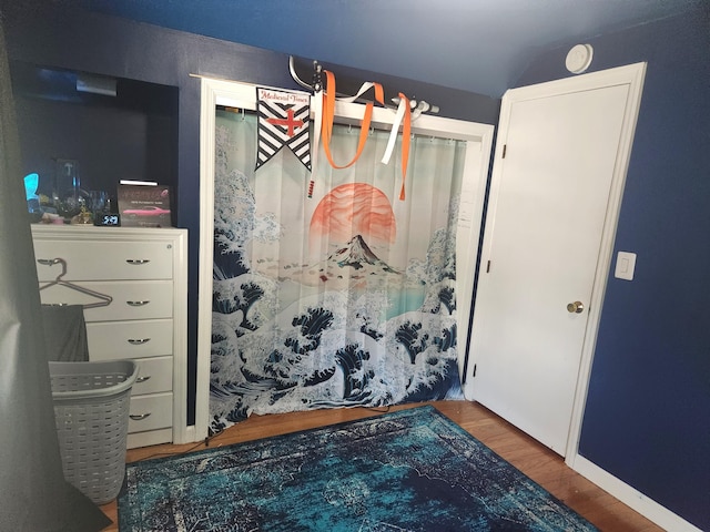 bedroom with wood finished floors and lofted ceiling