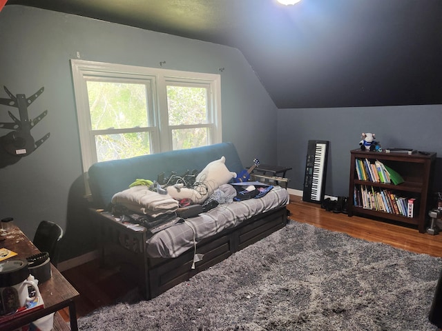bedroom with vaulted ceiling, wood finished floors, and baseboards