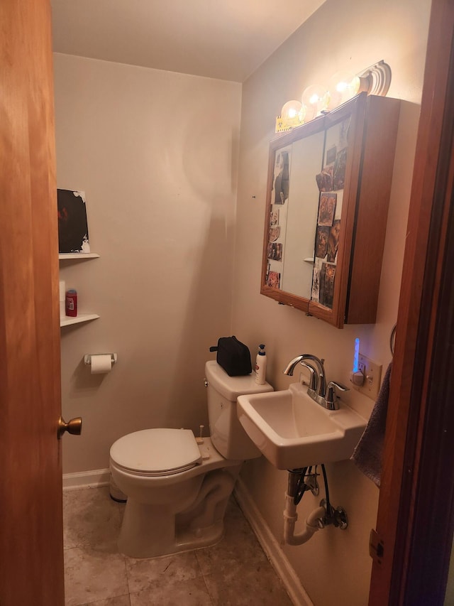 half bath with toilet, baseboards, and a sink