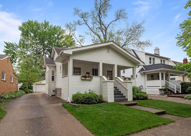 view of front of house featuring an outbuilding, covered porch, a detached garage, and a front yard