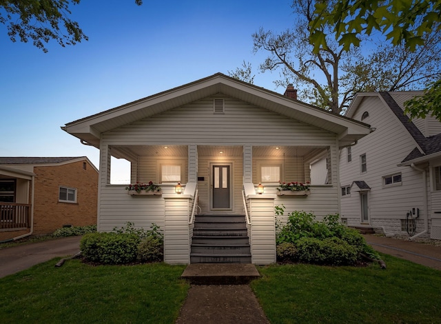 bungalow-style house featuring a front yard, entry steps, a chimney, and a porch