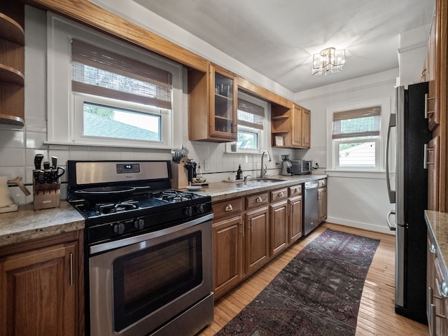 kitchen featuring open shelves, appliances with stainless steel finishes, decorative backsplash, a chandelier, and light wood-style floors