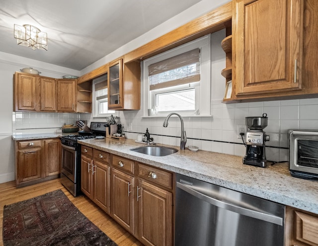 kitchen with stainless steel appliances, a sink, open shelves, and brown cabinetry