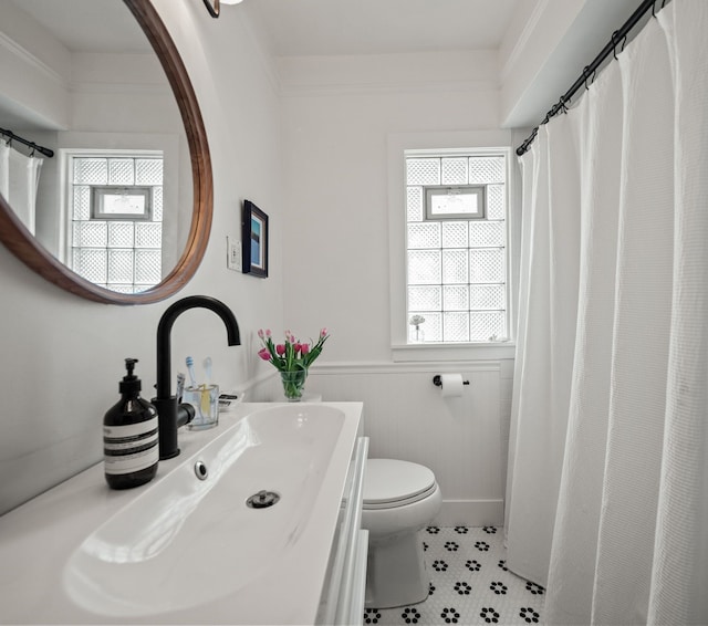 full bathroom featuring healthy amount of natural light, toilet, wainscoting, and vanity
