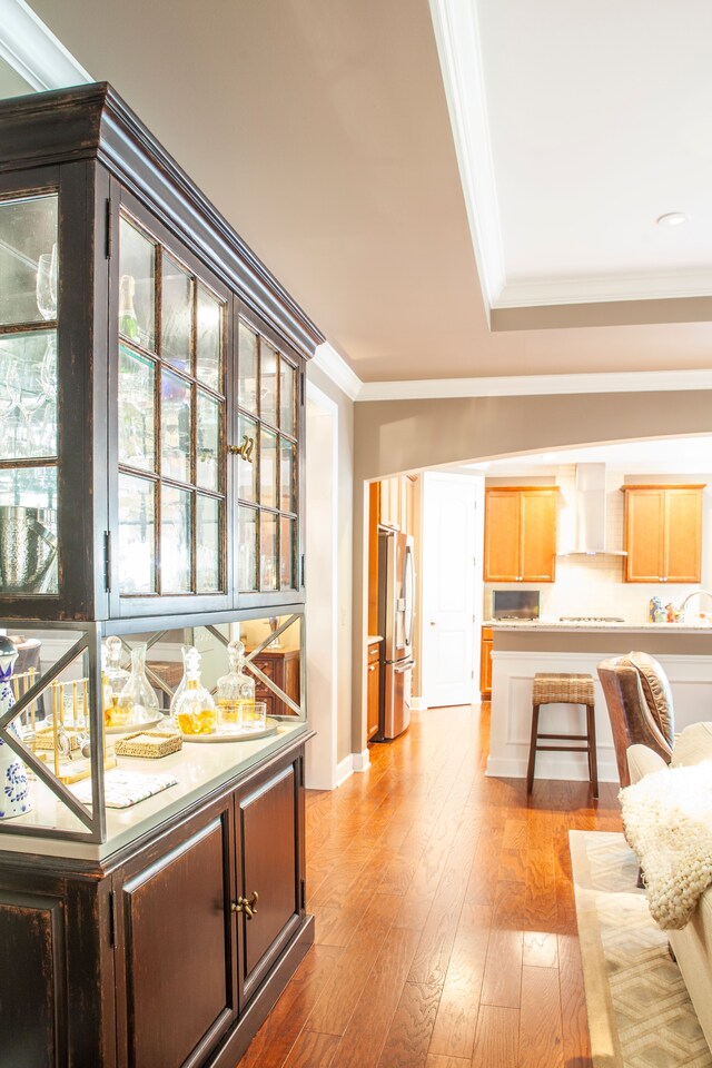 5514 Woodfall Rd, Clarkston, MI 48348 - kitchen with stainless steel fridge, wall chimney exhaust hood, crown molding, wood finished floors, and light brown cabinetry