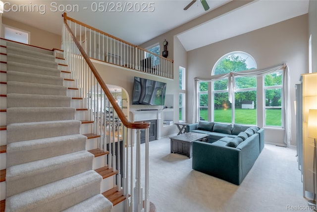 105 Crescent Hill Dr, Ortonville, MI 48462 - living room with high vaulted ceiling, stairs, a glass covered fireplace, carpet, and healthy amount of natural light