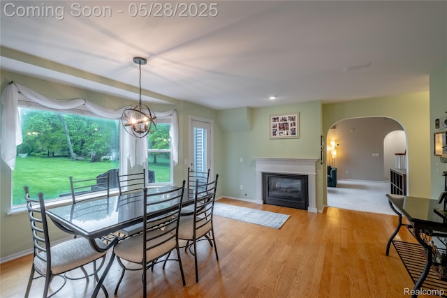 105 Crescent Hill Dr, Ortonville, MI 48462 - dining space with arched walkways, a glass covered fireplace, light wood-type flooring, baseboards, and a chandelier