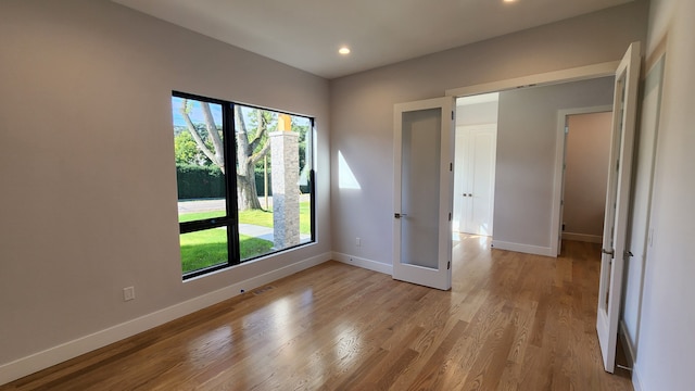 empty room featuring baseboards, healthy amount of natural light, light wood finished floors, and recessed lighting