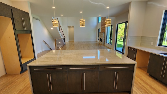 kitchen with healthy amount of natural light, light wood-style floors, backsplash, dark brown cabinetry, and recessed lighting