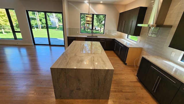 kitchen with light wood-style floors, light stone countertops, decorative backsplash, healthy amount of natural light, and recessed lighting