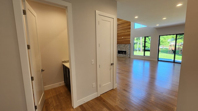 corridor with baseboards, wood finished floors, and recessed lighting