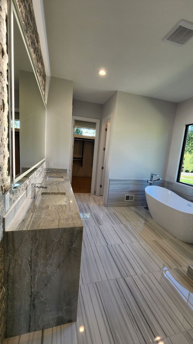 bathroom with a freestanding bath, double vanity, and recessed lighting