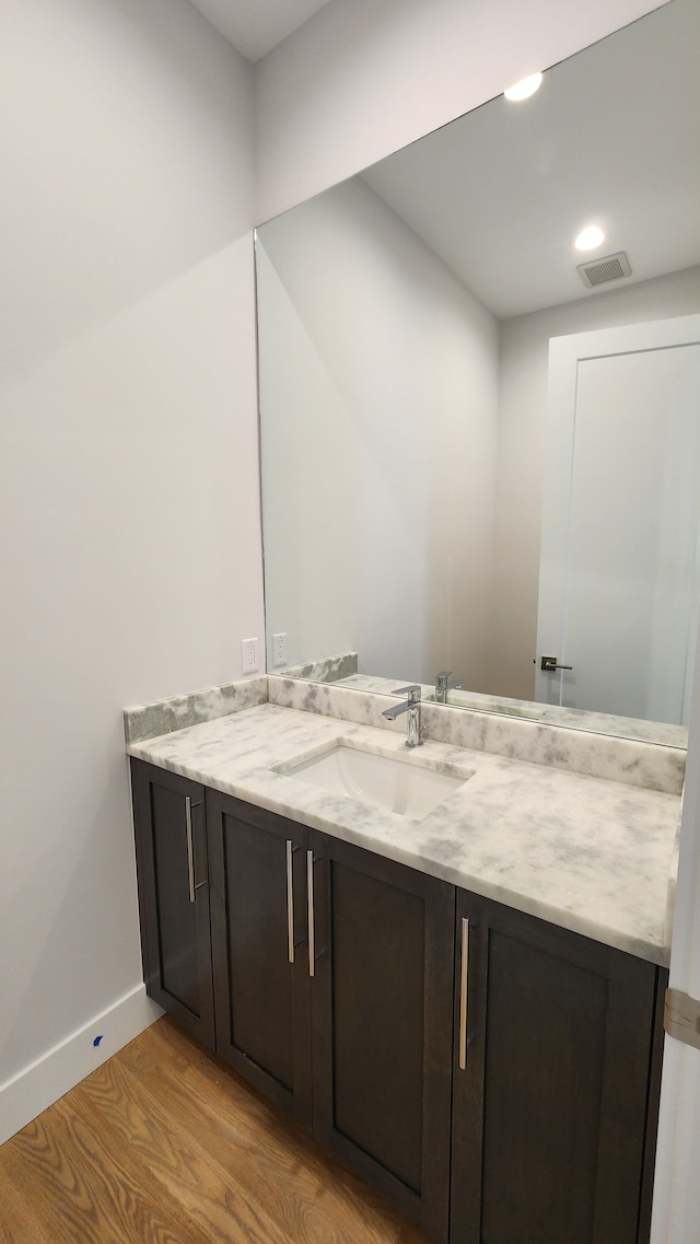 bathroom featuring wood finished floors, vanity, baseboards, and recessed lighting