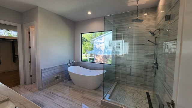 full bath featuring a shower stall, a freestanding tub, and recessed lighting