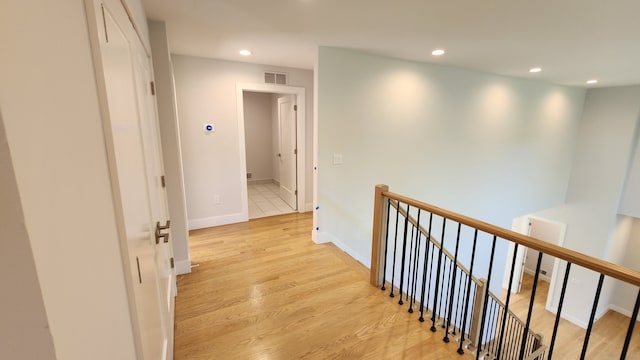 hall featuring an upstairs landing, recessed lighting, light wood-style flooring, and baseboards