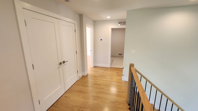 corridor with an upstairs landing, recessed lighting, light wood-style floors, and baseboards