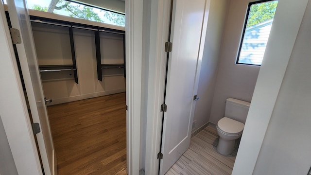 bathroom with wood finished floors, toilet, and baseboards