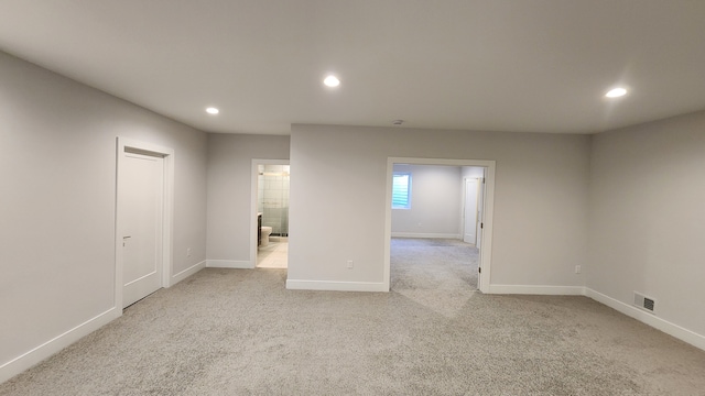 empty room featuring recessed lighting, light colored carpet, and baseboards