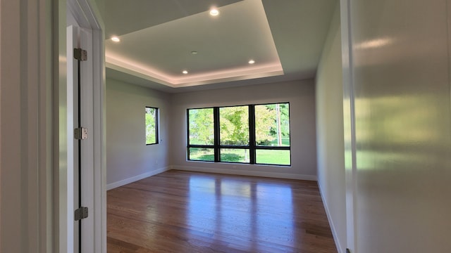 spare room featuring baseboards, wood finished floors, recessed lighting, and a raised ceiling