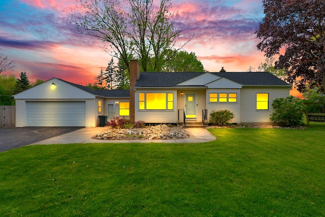 ranch-style home with a chimney, asphalt driveway, a lawn, an attached garage, and roof with shingles