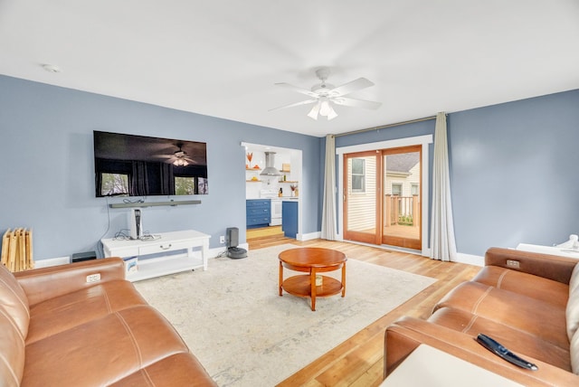living room featuring ceiling fan, baseboards, and wood finished floors