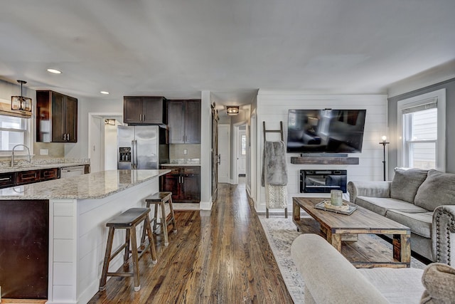 living room with dark wood-style flooring, a glass covered fireplace, and recessed lighting