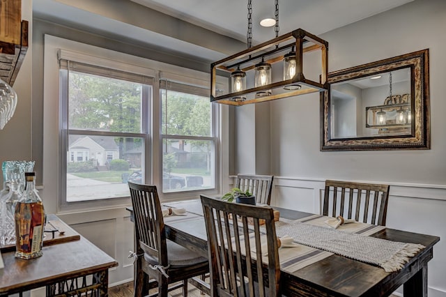 dining area featuring a decorative wall, wainscoting, and wood finished floors