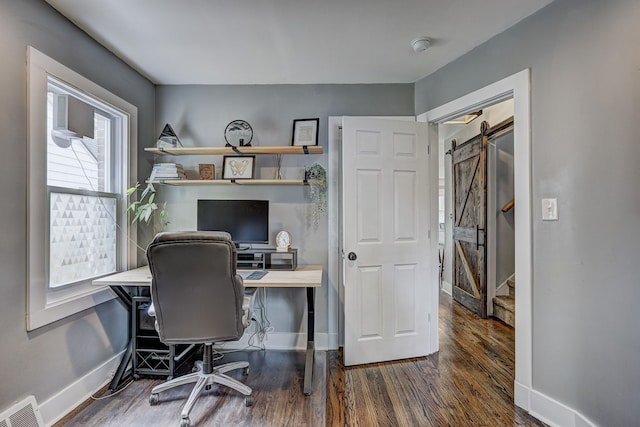 office area featuring baseboards, a barn door, and wood finished floors