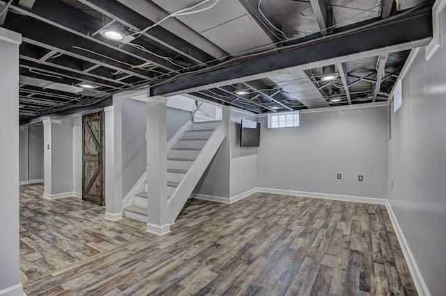 below grade area with wood finished floors, stairway, and baseboards
